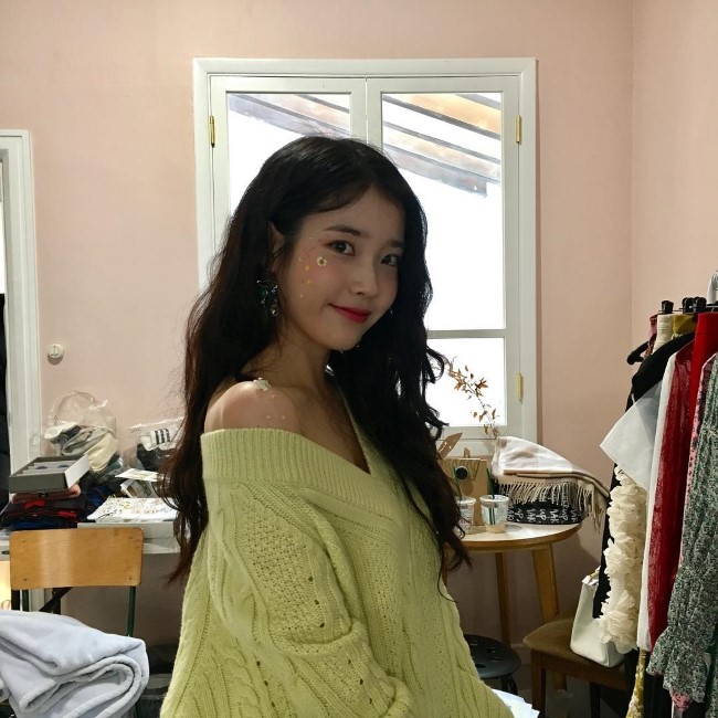 公开的照片中,iu 穿著淡黄色的毛衣小露香肩,一头浪漫的长卷发相当